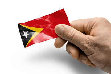 Hand holding a card with a national flag the East Timor