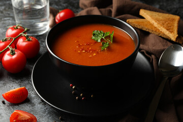 Concept of tasty food with tomato soup on black smokey background