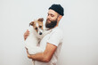 © San4ezz007 - A young guy, a hipster with a beard, holds on arms and hugs his dog, Jack Russel Terrier. True friendship. Animal lover