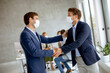 © BGStock72 - Young business men handshaking in the office with protective facial masks