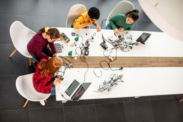 Wall Mural - Happy kids programming electric toys and robots at robotics classroom