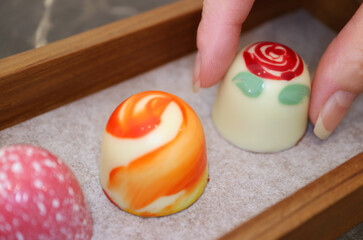 Wall Mural - Woman's Fingers Picking a Delectable and Beautiful White Chocolate Bonbon  