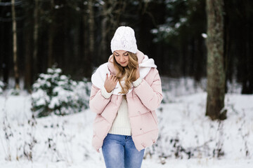 young beautiful woman in winter clothes in a winter park stands with her face down