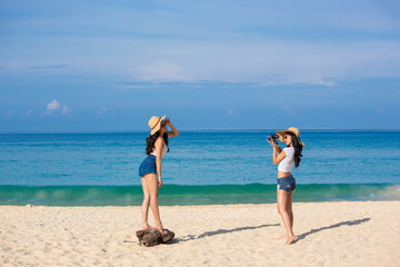 Wall Mural - Two happy women are sitting on the beach While relaxing on vacation for the weekend on sunny days and nice weather in travel and holiday concept.