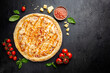 © petrrgoskov - Tasty pizza with chicken and Sweet and sour sauce and cooking ingredients tomatoes and basil on black background. Top view