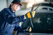 © zephyr_p - Young Asian auto mechanic checking windshield wiper in auto service garage. Mechanical maintenance engineer working in automotive industry. Automobile servicing and repair