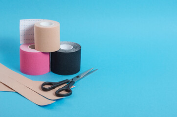 Kinesiological multi-colored tapes for fixing muscles during sports and after injuries on a blue background with a copy space.