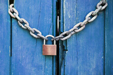 Golden Padlock And Chains On Blue Old Wooden Door Background.