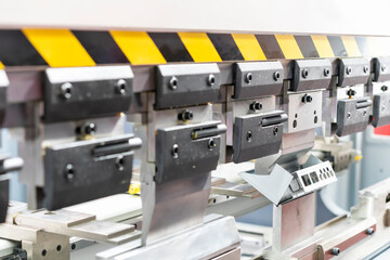 Wall Mural - Close up teeth of the semi automatic hydraulic bending machine and the metal sheet or the workpiece during folding forming