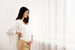 Portrait shot of young beautiful woman on second trimester of pregnancy. Close up of pregnant female in casual attire with arms on her round belly. Expecting a child concept. Background, copy space.