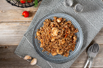 Buckwheat porridge with meat and vegetables in a ceramic plate on a gray wooden table. Buckwheat for a healthy diet	