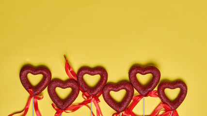 Greeting card or banner for Valentine's Day. red bright hearts with ribbons on a yellow background top view. flat lay.