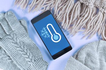 concept for cold temperatures with snow and minus degrees with mobile phone showing weather forecast