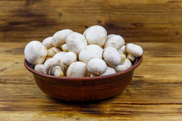 Poster - Fresh champignon mushrooms in ceramic bowl on the wooden table