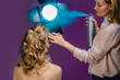 © Miramiska - Stylist makes girl's hair, hair spray. Combing female hair. Hair care for woman. Stylist makes an evening hairstyle for model at photo shoot applies hairspray.