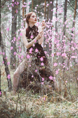 Wall Mural - Japanese-style girl in a flowering forest among pink flowers in spring