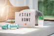 © interstid - Stay home sign lightbox with hashtag with dumbbell and water bottle in living room to promote self isolation and workout at home during COVID-19