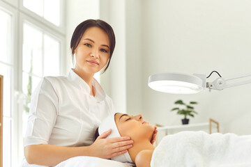 Wall Mural - Woman dermatologist touching young womans face during checking skin or massage