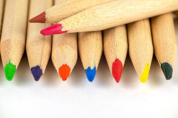 row of light wooden pencils with colored cores close up on gray blurred background