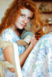 © Oleksandra - Portrait of cute redhead woman  with freckles in blue dress sitting with teddy bear toy at home. Natural beauty. Woman's Day. Greeting card.