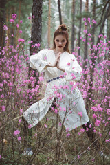 Poster - Japanese-style girl in a flowering forest among pink flowers in spring