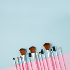 Wall Mural - Set of fashion makeup brushes on pastel pink and blue background. Beauty cosmetic makeup product layout. Creative fashionable concept. Cosmetics make-up brushes collection, flat lay, top view.