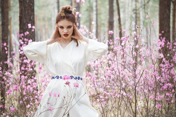 Wall Mural - Japanese-style girl in a flowering forest among pink flowers in spring