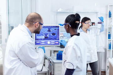 Wall Mural - african scientist and doctor studying cure for dangerous virus on computer in busy laboratory. multi