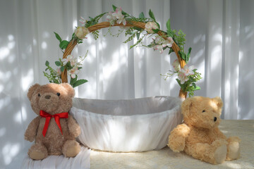 basket wrapped with white cloth there are flowers around the handle. and a teddy bear beside