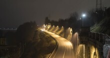 Night Time Lapse Of Cars Driving On Road. Famous Stone Wall In Small Town Kranj, Slovenia. Light Trails From Cars. Zoom In