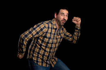 Attractive bearded man in a yellow plaid shirt posing isolated on black background