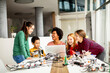 © BGStock72 - Happy kids with their African American female science teacher with laptop programming electric toys and robots at robotics classroom