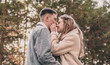 © Катя Данилюк - A girl holds a guy by the face with her hands and smiles at him while walking in a pine forest