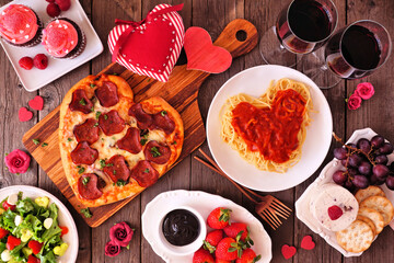 Aufkleber - Home cooked Valentines Day dinner. Top view table setting on a dark wood background. Heart shaped pizza, pasta, wine, cheese plate and desserts.