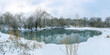 Panoramic landscape with snowy trees, beautiful lake with reflection in water. Scenic winter landscape