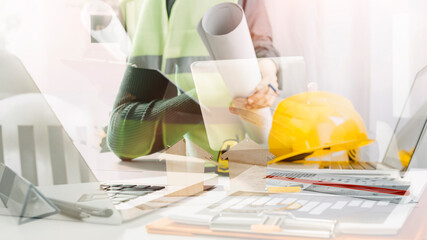 Two colleagues discussing data working and tablet, laptop with on on architectural project at construction site at desk in office