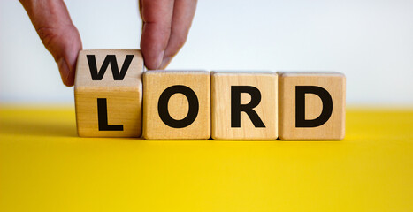 The word of the Lord symbol. Hand turns the wooden cube and changes the word 'Lord' to 'word' on a beautiful yellow table, white background. Word the Lord concept. Copy space.
