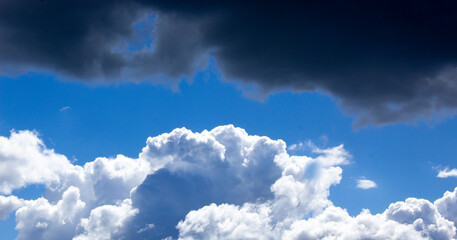 Sky with white and black clouds and sun. Beautiful background, copy space.