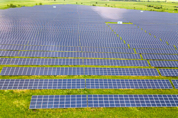 Aerial view of solar power plant on green field. Electric panels for producing clean ecologic energy.