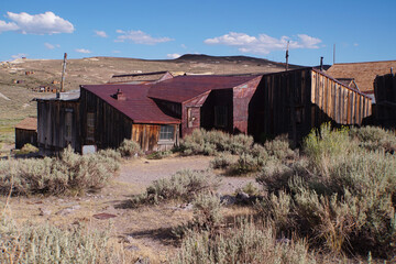 Wall Mural - Abandoned buildings at the abandoned Bodie ghost town in the Sierra Nevada mountains of California on a sunny day with clouds