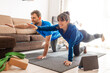 Couple exercising in living room following video from tablet, woman and man stretched out on exercise mat with tablet and yoga blocks.