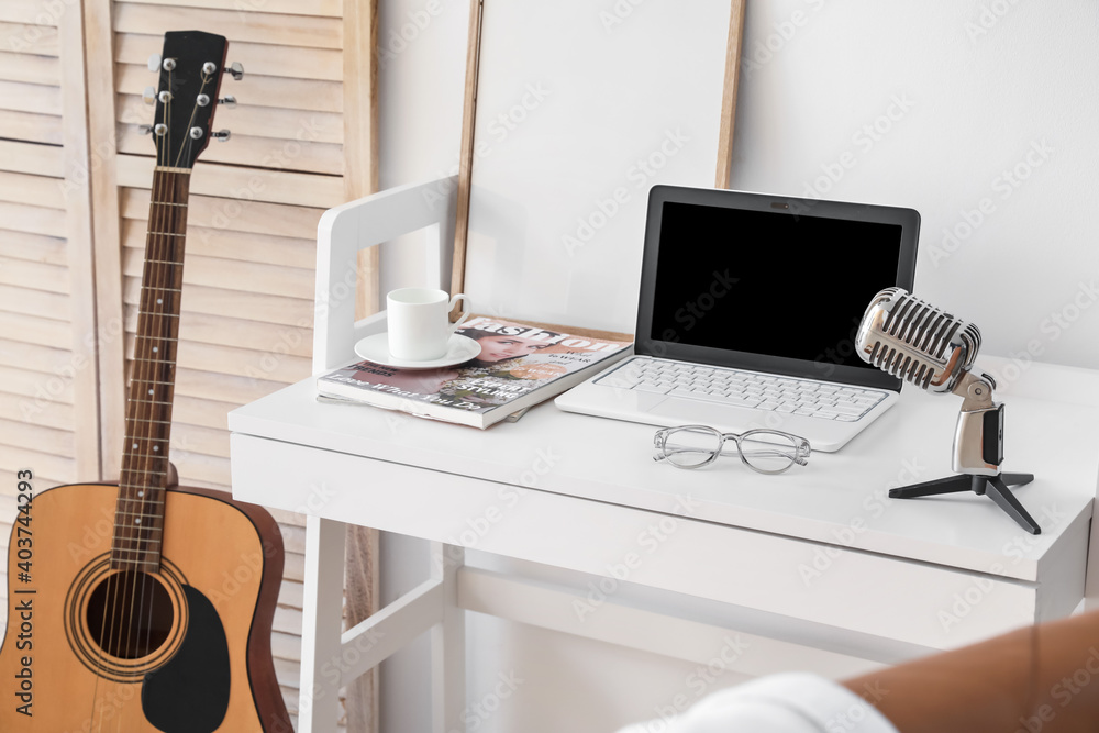 Comfortable workplace with modern laptop near light wall