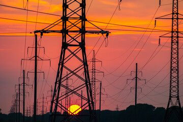 power poles against the setting sky and a large sun