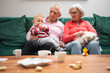 © Vesna - Grandparents with their young grandson and poodle dog sitting in the living room
