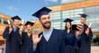 © Syda Productions - education, graduation and people concept - happy smiling male graduate student in mortar board and bachelor gown with smartphone having video call or taking selfie over school background