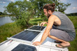 Man on top of a camper van next to solar panels