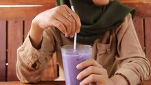 A Woman Is Enjoying Purple Ice In A Wooden Cafe. The Woman's Hand Stirs The Fresh Iced Grapes