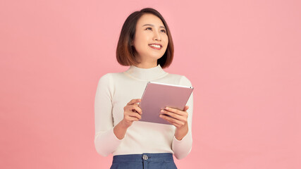 Wall Mural - Beauty at work. Confident young women holding digital tablet while standing against pink background