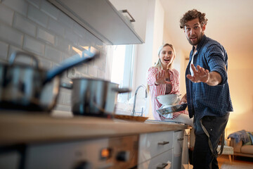 Wall Mural - A young couple is posing for a photo while doing housework. Kitchen, housework, home, relationship