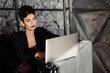 © shunevich - Beautiful gorgeous female boss in fashion dress sit at the sofa, using laptop. Stylish elegant business woman look at the screen, develop a project. Attractive leader of the company remotely working